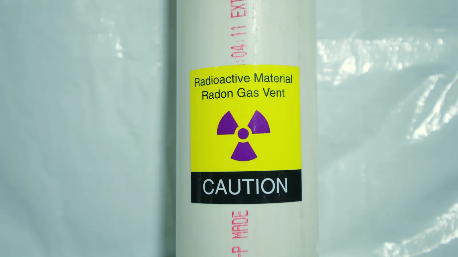 White PVC radon vent pipe with a radioactive-material caution placard
